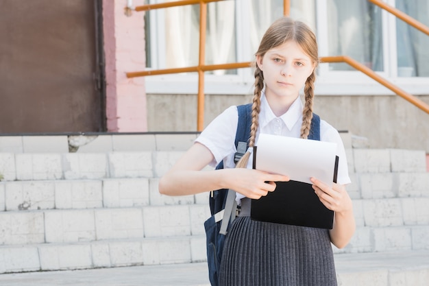 Ritratto di una studentessa giovane, bella, attraente e intelligente nell'indossare occhiali in una camicia bianca che fa una presentazione in una conferenza all'aperto. Sorride mentre si presenta