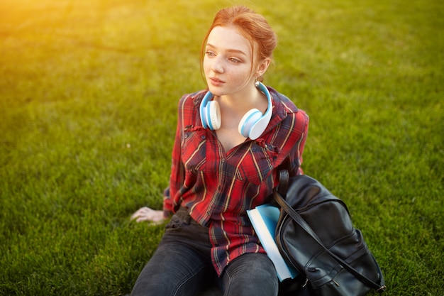 Ritratto di una studentessa giovane rossa ascoltando musica in cuffia