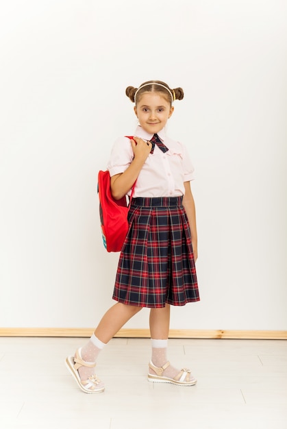 Ritratto di una studentessa in uniforme in piedi su sfondo bianco