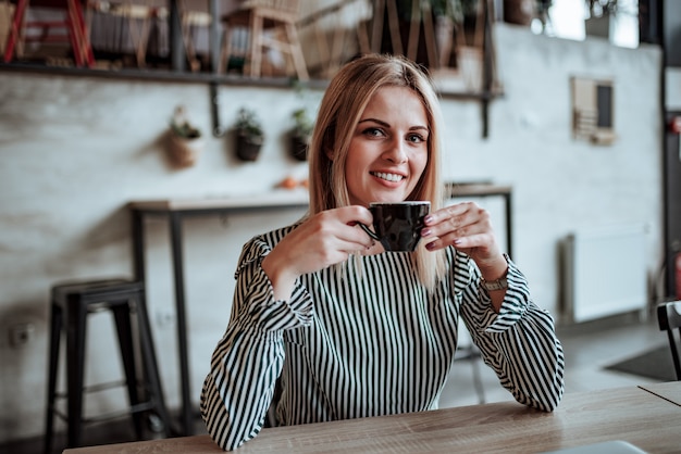 Ritratto di una tazza di caffè della holding della giovane donna.