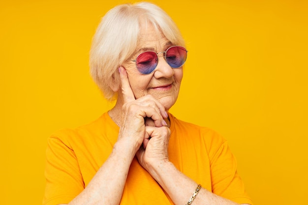 Ritratto di una vecchia donna amichevole in maglietta casual occhiali da sole sfondo giallo
