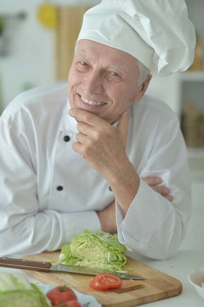 Ritratto di uno chef maschio anziano che cucina insalata