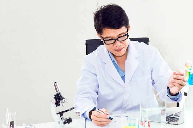 Ritratto di uno scienziato maturo sorridente in un cappotto bianco con lente di ingrandimento.