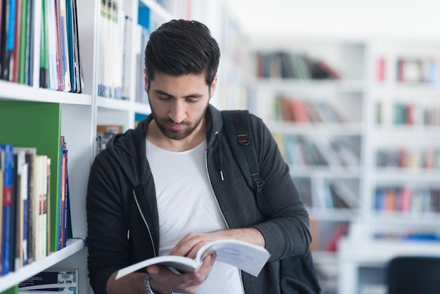 Ritratto di uno studente felice mentre legge un libro nella biblioteca scolastica Lezioni di studio per l'esame Concetto di duro lavoro e perseveranza