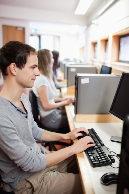 Ritratto di uno studente maschio serio che lavora con un computer