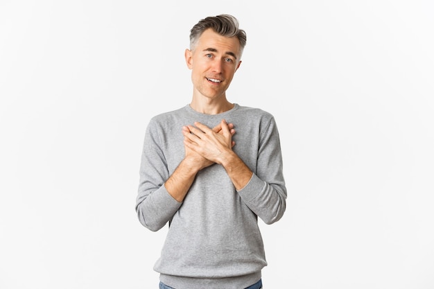 Ritratto di uomo adulto felice e felice con i capelli grigi, tenendo le mani sul cuore