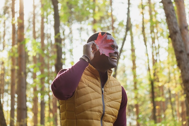 Ritratto di uomo afroamericano che copre il viso con foglia d'acero autunnale Natura autunnale Moda autunnale stagionale