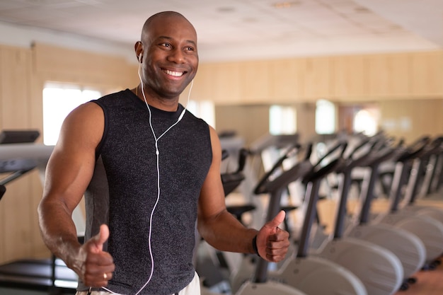 Ritratto di uomo afroamericano sorridente in palestra. Ha i pollici in su in atteggiamento positivo. Concetto di sport e vita sana.