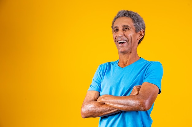 Ritratto di uomo anziano afro con le braccia incrociate sorridendo alla telecamera.