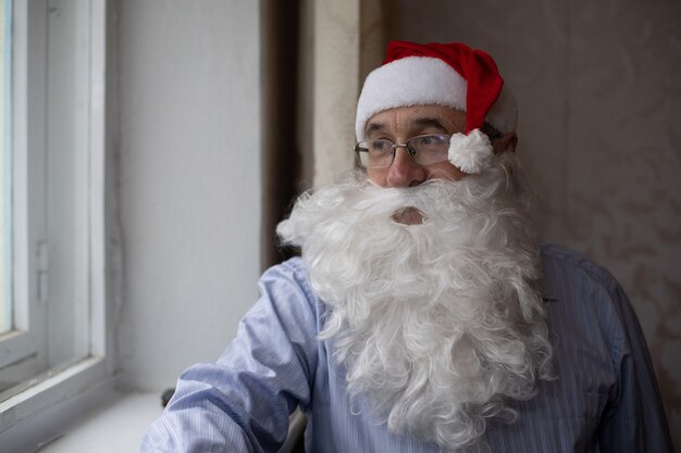 ritratto di uomo anziano con cappello da Babbo Natale che guarda l'obbiettivo