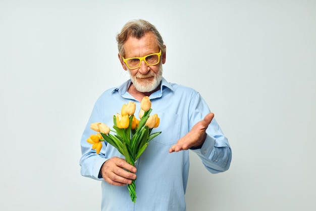 Ritratto di uomo anziano felice un mazzo di fiori con gli occhiali come sfondo chiaro regalo