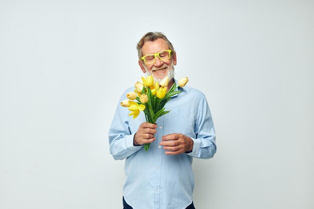 Ritratto di uomo anziano felice un mazzo di fiori con gli occhiali come sfondo chiaro regalo