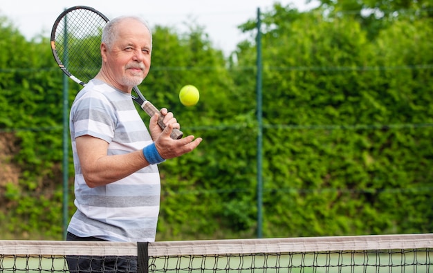 Ritratto di uomo anziano giocando a tennis in ab fuori, sport in pensione, concetto di sport