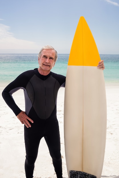 Ritratto di uomo anziano in muta tenendo una tavola da surf