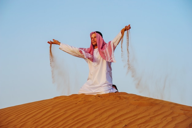 Ritratto di uomo arabo assetato in mezzo al deserto giallo.