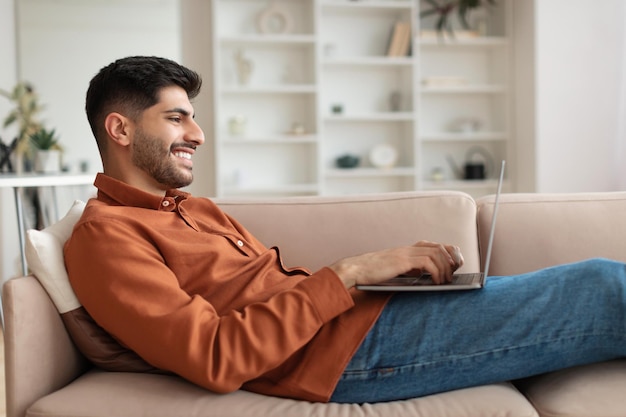 Ritratto di uomo arabo sorridente che utilizza il pc a casa