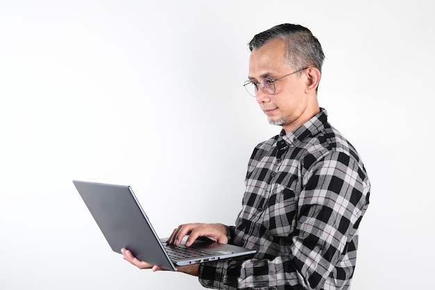 Ritratto di uomo asiatico adulto con gli occhiali in possesso di un computer portatile