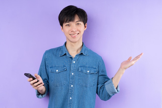 Ritratto di uomo asiatico in camicia blu in posa su sfondo viola