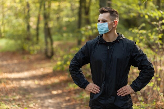 Ritratto di uomo attivo in maschera medica nella foresta