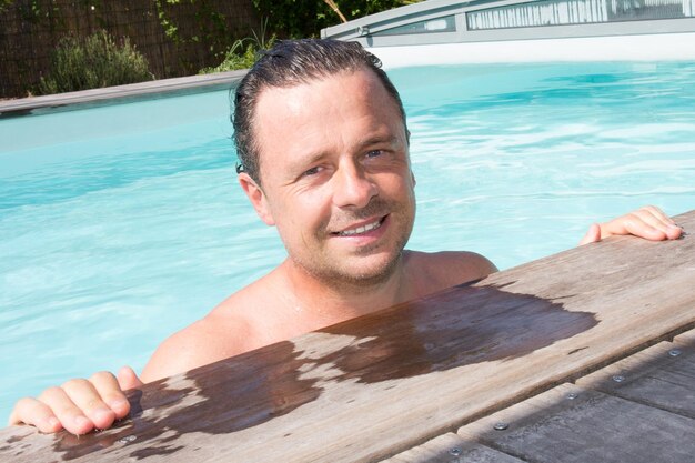 Ritratto di uomo bello che si rilassa nella piscina a bordo piscina in vacanza in acqua