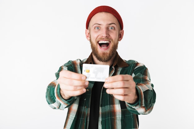 Ritratto di uomo caucasico ridendo e tenendo la carta di credito, mentre in piedi isolato su sfondo bianco