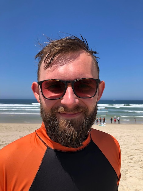 Ritratto di uomo che indossa occhiali da sole sulla spiaggia contro il cielo
