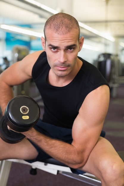 Ritratto di uomo che si esercita con dumbbell in palestra