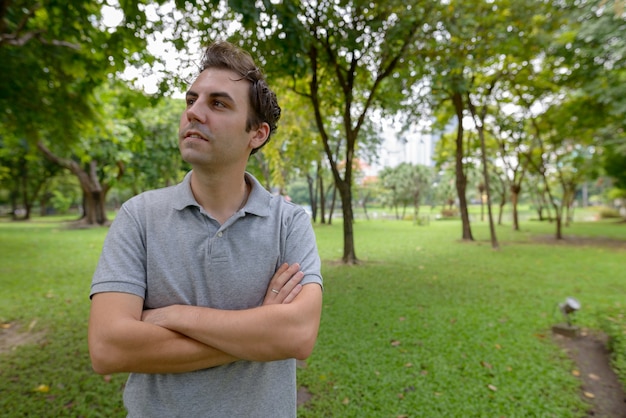 Ritratto di uomo con capelli castani rilassante presso il parco all'aperto