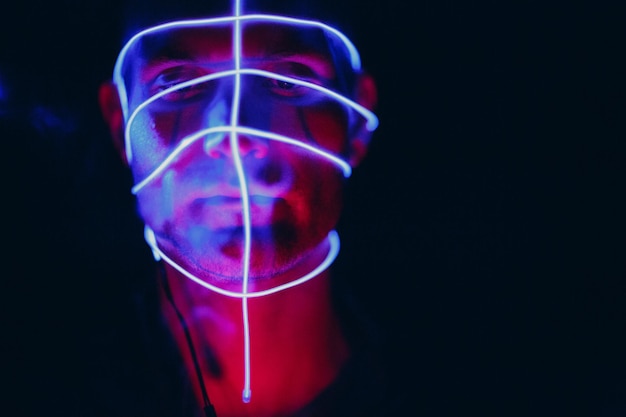 Ritratto di uomo con linee di bagliore al neon sul viso Concetto cyberpunk e realtà virtuale