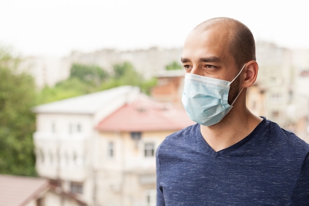 Ritratto di uomo con maschera sul balcone durante la pandemia globale.