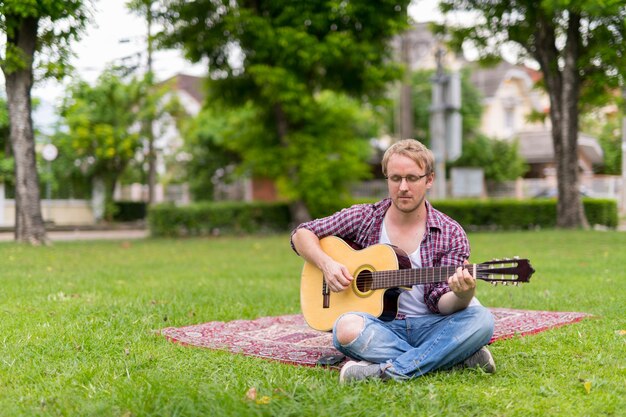 Ritratto di uomo con picnic mentre si suona la chitarra all'aperto