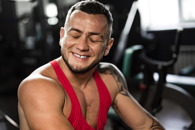 Ritratto di uomo culturista in camicia rossa in palestra