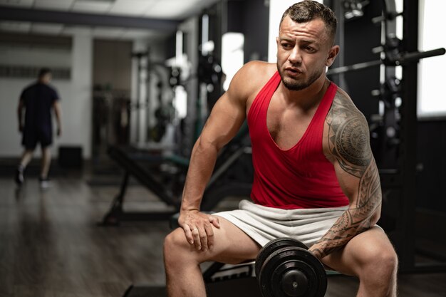 Ritratto di uomo culturista in camicia rossa in palestra