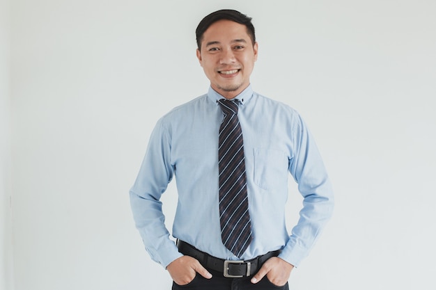 Ritratto di uomo d'affari sorridente che indossa camicia blu e cravatta in posa con fiducia su sfondo bianco