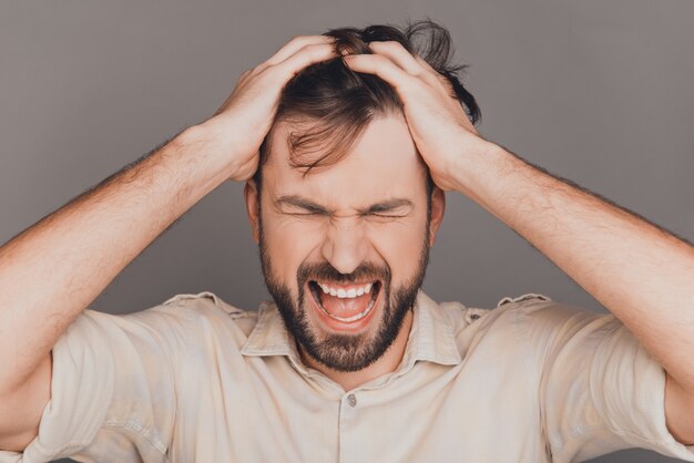 Ritratto di uomo depresso nervoso che tocca i capelli e che grida