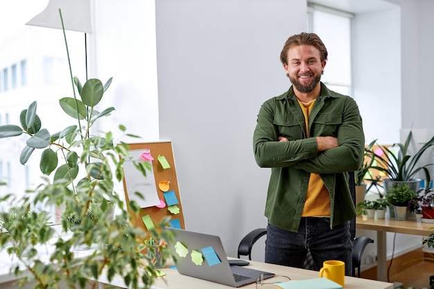 Ritratto di uomo di design manager caucasico eccitato in ufficio che posa alla macchina fotografica