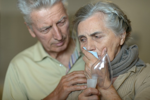 Ritratto di uomo e donna anziani con inalazione di influenza