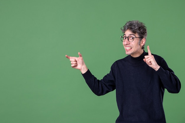 Ritratto di uomo genio vestito casualmente in studio girato su parete verde