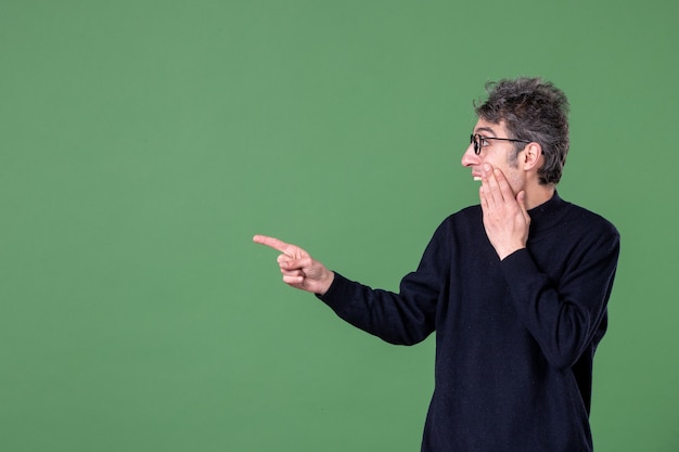 Ritratto di uomo genio vestito casualmente in studio girato su parete verde