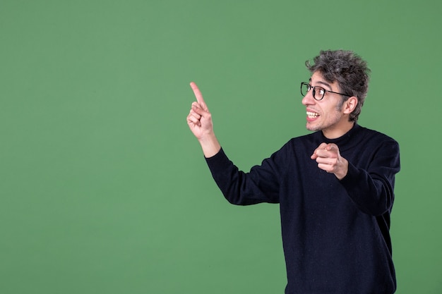 Ritratto di uomo genio vestito casualmente in studio girato su parete verde