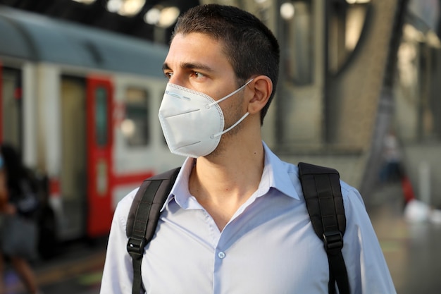 Ritratto di uomo in attesa del treno con maschera protettiva alla stazione ferroviaria