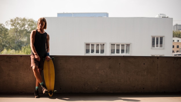 Ritratto di uomo in piedi con un longboard