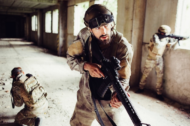 Ritratto di uomo in uniforme in piedi nella stanza vuota con altri soldati e in attesa.