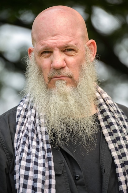 Ritratto di uomo maturo hipster calvo con barba lunga al parco all'aperto