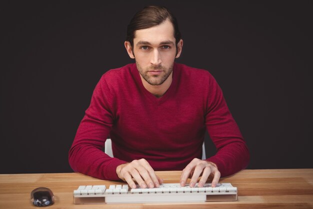 Ritratto di uomo serio digitando sulla tastiera alla scrivania