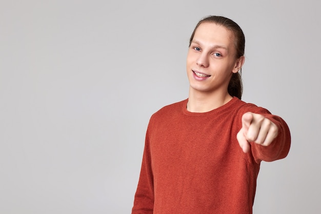 Ritratto di uomo sorridente che punta alla telecamera isolata su sfondo grigio