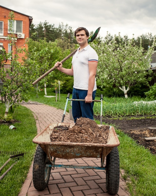 Ritratto di uomo sorridente con vanga e carriola da giardino