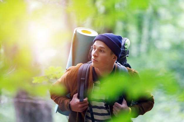 Ritratto di uomo viaggiatore con zaino che attraversa la foresta