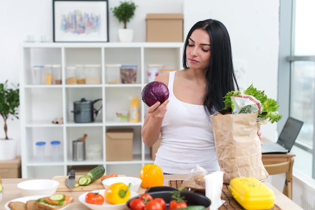 Ritratto di vista frontale di una casalinga che guarda attentamente e tiene il cavolo scegliendo un buon ingrediente fresco per la sua insalata vitaminica