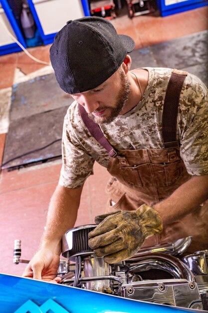 Ritratto di vista laterale dell'uomo che lavora in garage riparazione moto e personalizzazione